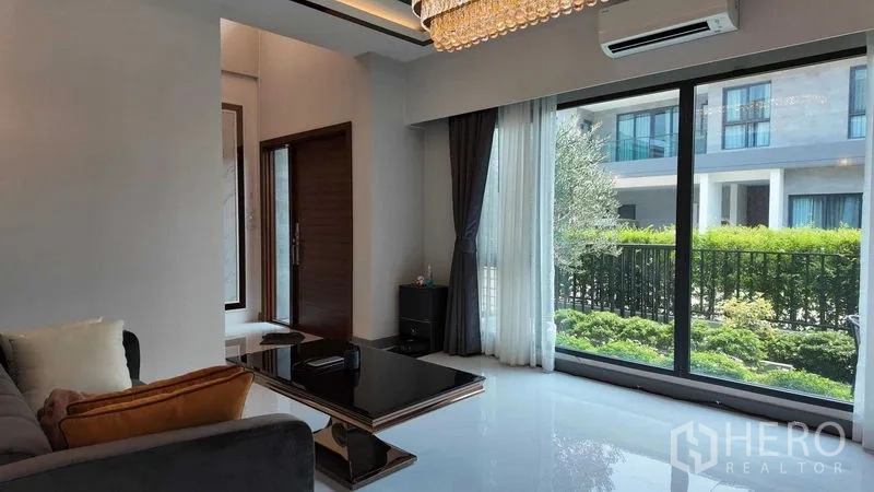 独立式住宅 出租或出售在Bang Na, Bangkok - 采光充足的客厅，落地推拉门面向前花园。