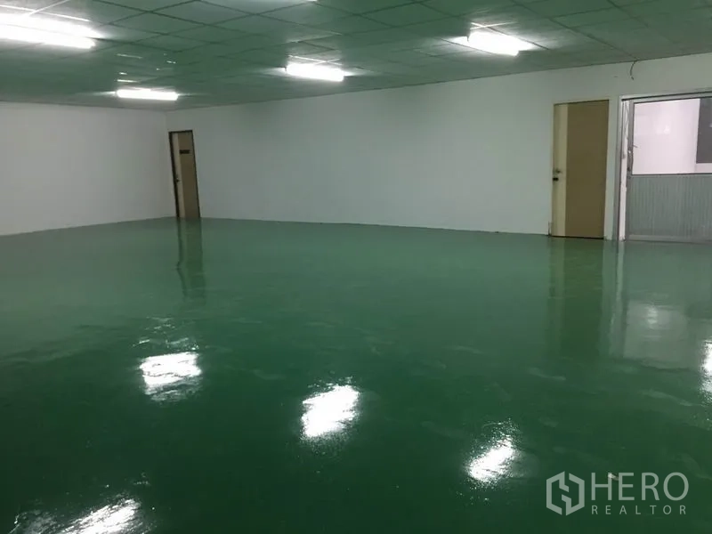 Factory for rent in Lam Luk Ka, Pathum Thani - Spacious clean room with polished epoxy flooring, multiple doors and bright overhead lights.