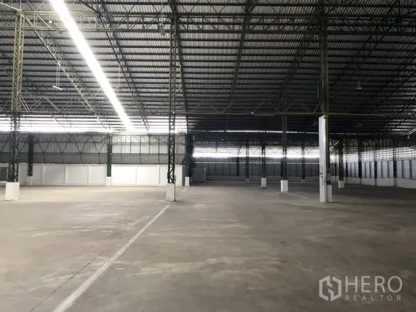 Warehouse for rent in Mueang Pathum Thani, Pathum Thani - Empty warehouse hall with marked drive lanes, high ceiling and ventilated side panels for airflow.