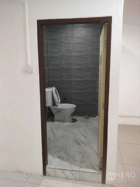 Shophouse for sale in Phra Khanong, Bangkok - Renovated bathroom with gray wall tiles and a toilet.