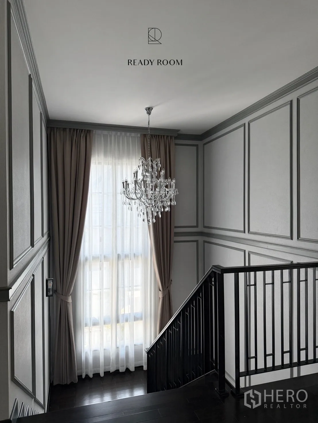 Detached House for rent or sale in Bang Phli, Samut Prakan - Staircase landing with black railing, tall curtained window and a hanging crystal chandelier.