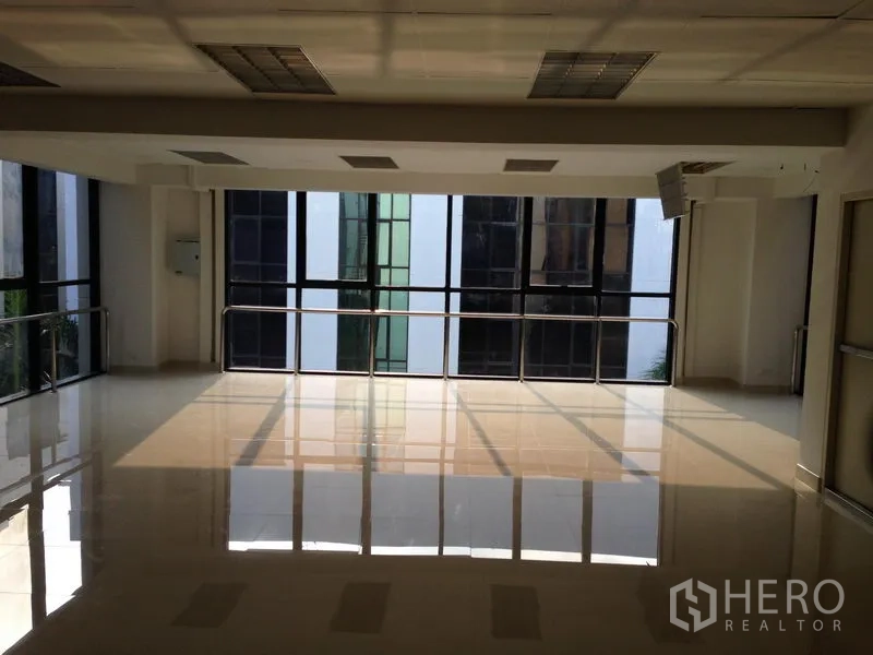 Office Space for rent in Bang Kapi, Bangkok - Bright open-plan office with glossy tiled floors, large windows and ceiling lights overlooking a neighboring building.