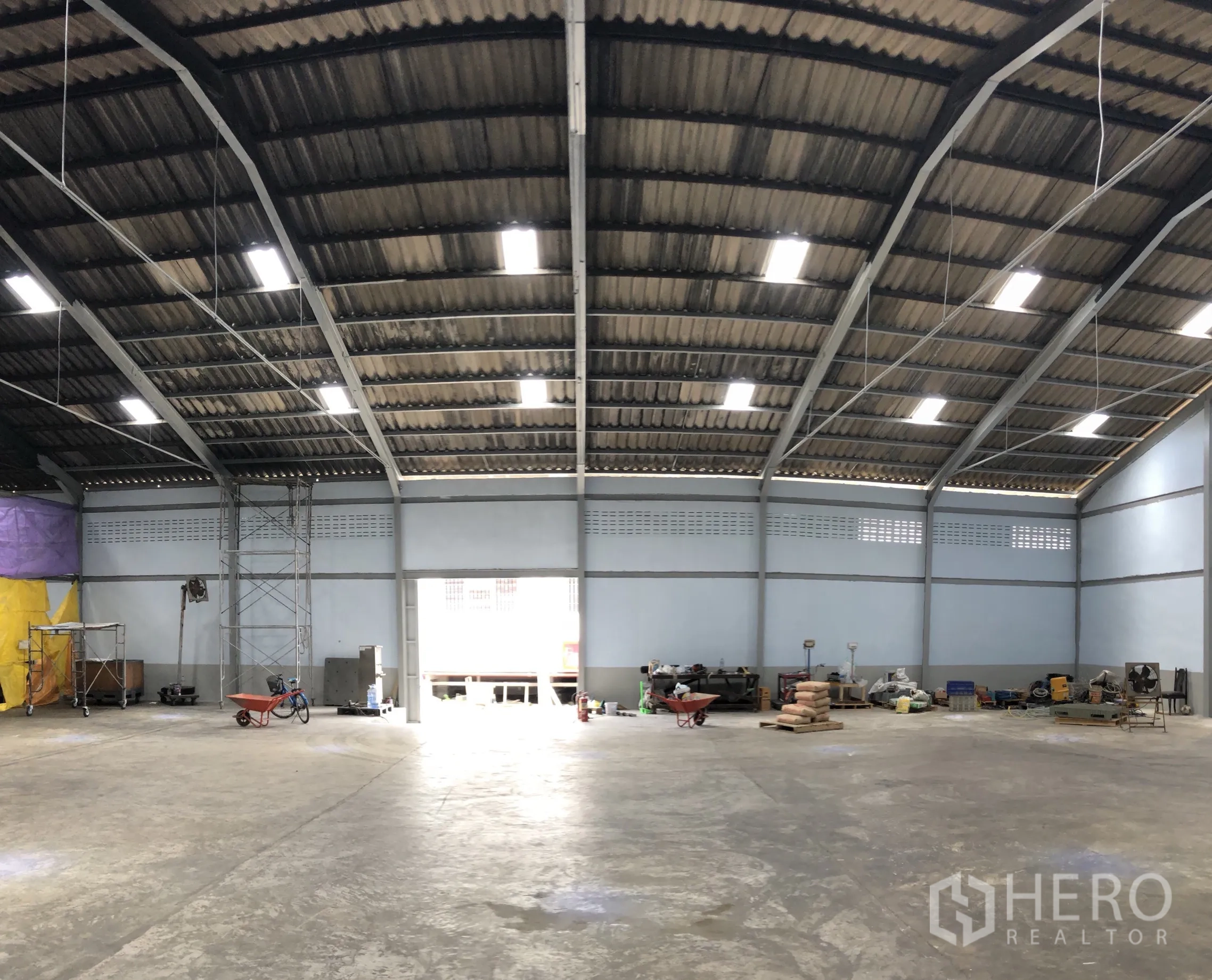 Factory for rent in Mueang Samut Prakan, Samut Prakan - Open-plan warehouse space with tools and natural light from a large doorway.