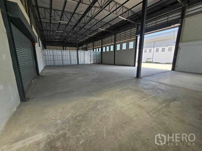 Warehouse for rent in Bang Bua Thong, Nonthaburi - Spacious storage bay with large entry opening, steel columns and ventilated side panels.