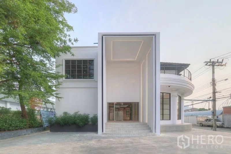 Office Space for rent in Bang Na, Bangkok - Modern white office building in Bang Na with a grand double‑height entrance and LED lighting near BTS Bearing.