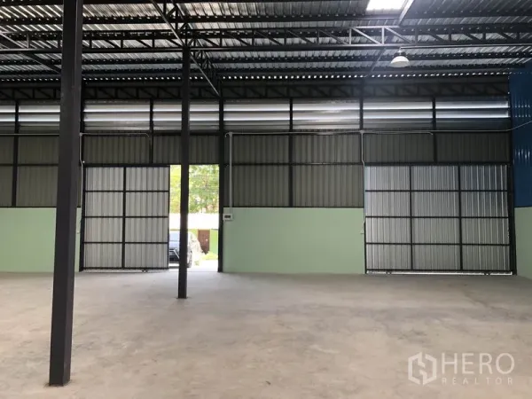 Warehouse for rent in Khlong Luang, Pathum Thani - Spacious warehouse interior with high steel truss roof, concrete floor and large sliding gates.
