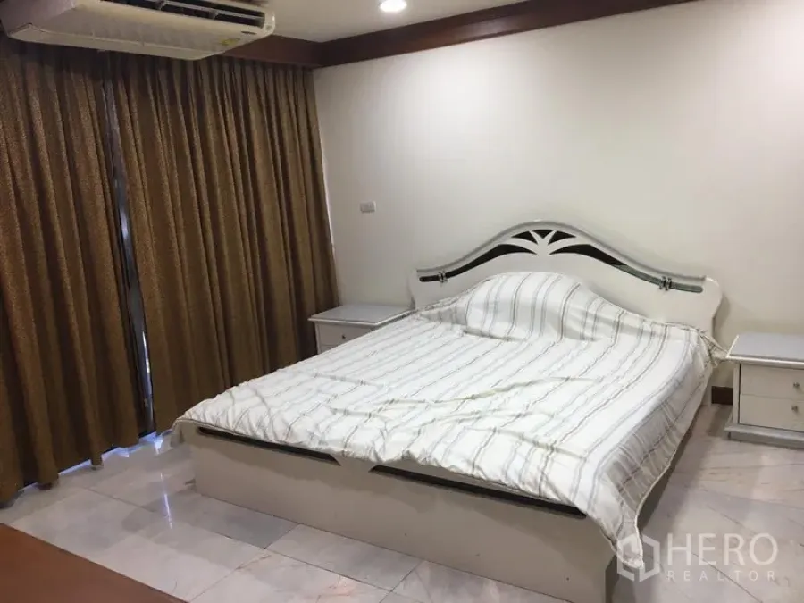 Condominium for rent or sale in Watthana, Bangkok - Master bedroom with white bed, bedside tables and full-length curtains in a Watthana condo.