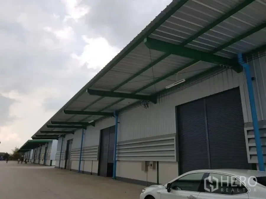 Warehouse for rent in Bang Phli, Samut Prakan - Close-up of warehouse facade with deep canopy, roller shutters and parking area.