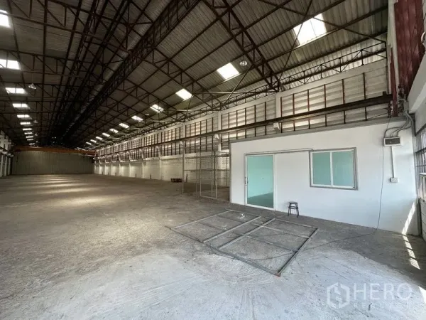 货栈 出租在Lam Luk Ka, Pathum Thani - 宽敞仓库内部，高钢桁架屋顶与天窗，混凝土地面，配玻璃门办公室。
