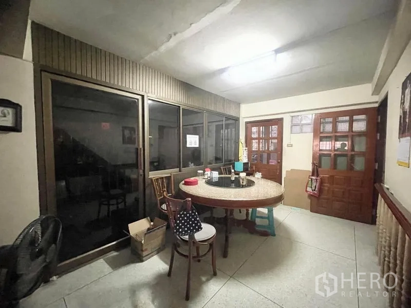 Townhouse for rent in Sathon, Bangkok - Dining area with round table, glass partition and wooden doors in a Sathon townhouse.