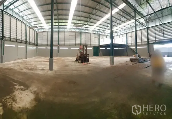 Factory for rent in Saphan Sung, Bangkok - Large clear‑span factory floor under skylights with steel columns, forklift and a mezzanine platform.