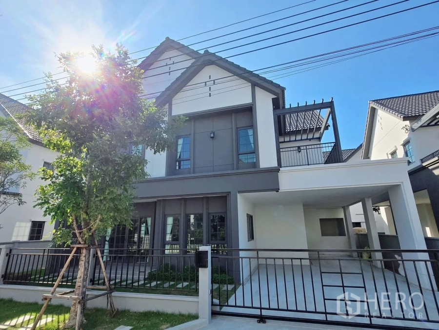 Detached House for rent or sale in Bang Phli, Samut Prakan - Modern two‑storey detached house exterior with gable roof, covered carport and gated yard.