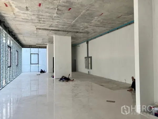 Retail Space for rent in Khlong Toei, Bangkok - Long rectangular retail space with high ceiling, electrical panel, and a full window wall.