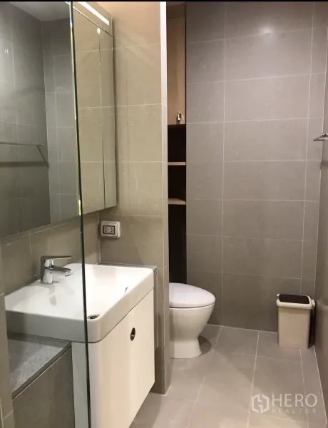 Condominium for rent in Pathum Wan, Bangkok - Contemporary bathroom with glass shower enclosure, tiled walls, vanity and toilet.
