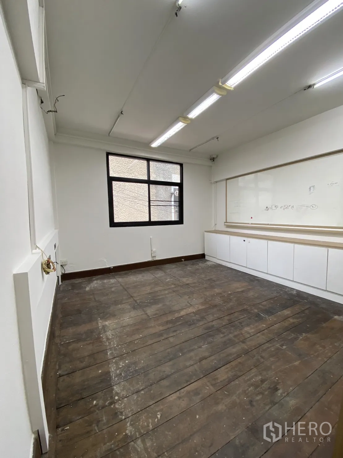 Shophouse for rent - Bright office-style room with fluorescent lighting, window and long counter cabinets.