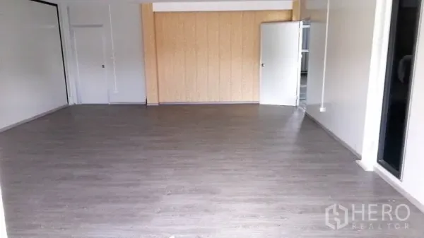 Warehouse for rent or sale in Lam Luk Ka, Pathum Thani - Air-conditioned office area with wood-look flooring, neutral walls, and large sliding glass entry.