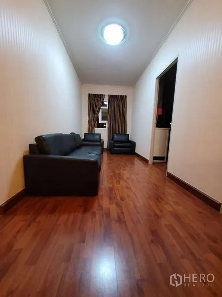 Detached House for rent - Upstairs lounge with wood floors, dark sofas and small window.