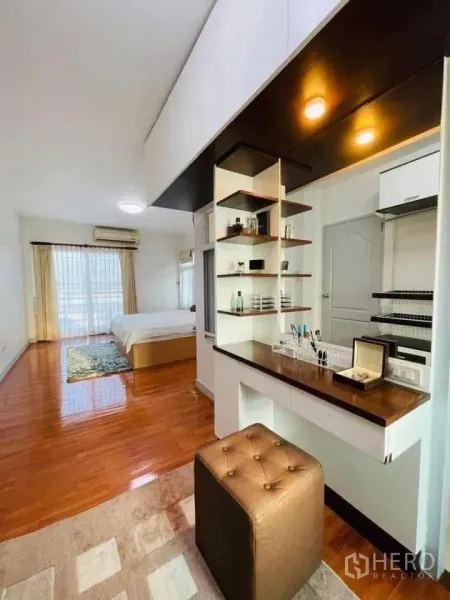Detached House for rent or sale in Lam Luk Ka, Pathum Thani - Master bedroom with wooden floors, built-in vanity and open shelving leading to sleeping area.