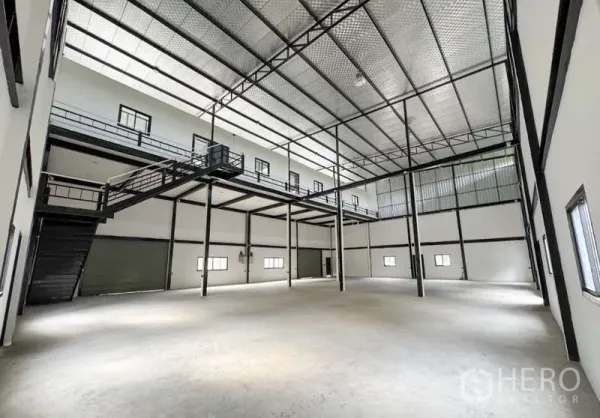 Warehouse for rent in Bang Phli, Samut Prakan - Spacious warehouse interior with high insulated ceiling, steel columns, mezzanine walkway and a roller‑shutter loading bay.