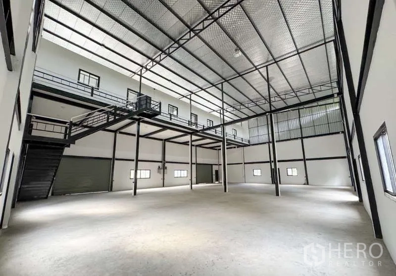Warehouse for rent in Bang Phli, Samut Prakan - Spacious warehouse interior with high insulated ceiling, steel columns, mezzanine walkway and a roller‑shutter loading bay.