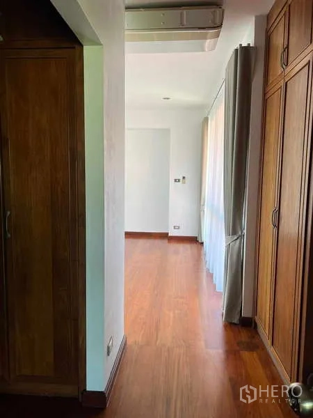 Detached House for rent in Bang Phli, Samut Prakan - Hallway with built-in wardrobes, wooden floors and natural light through curtained windows.