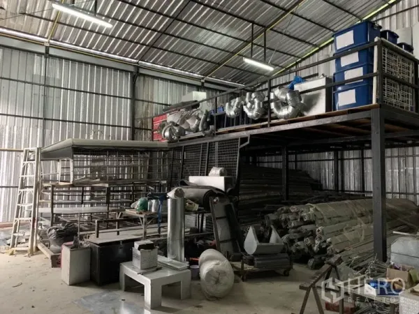 Warehouse for rent in Bang Kapi, Bangkok - High-ceiling warehouse with steel mezzanine storage racks and ducting materials.
