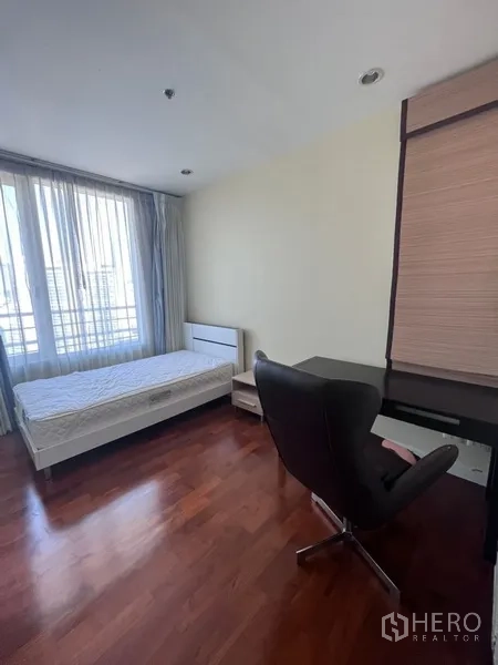 Condominium for rent in Khlong Toei, Bangkok - Third bedroom with single bed, work desk, wardrobe and tall window with sheer curtains.