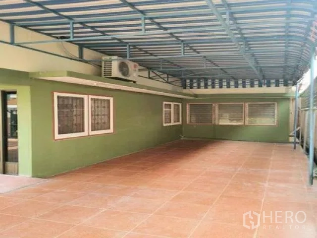 Home Office for rent in Wang Thonglang, Bangkok - Covered carport area with green exterior walls, security-grilled windows and terracotta floor tiles.