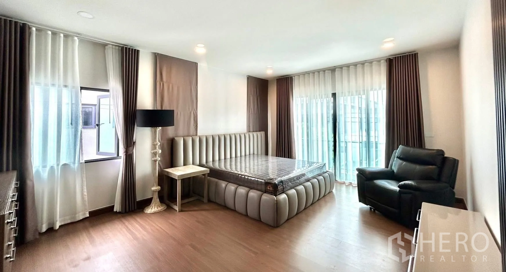 Detached House for rent in Bang Phli, Samut Prakan - Spacious master bedroom with upholstered bed, recliner, and balcony doors.