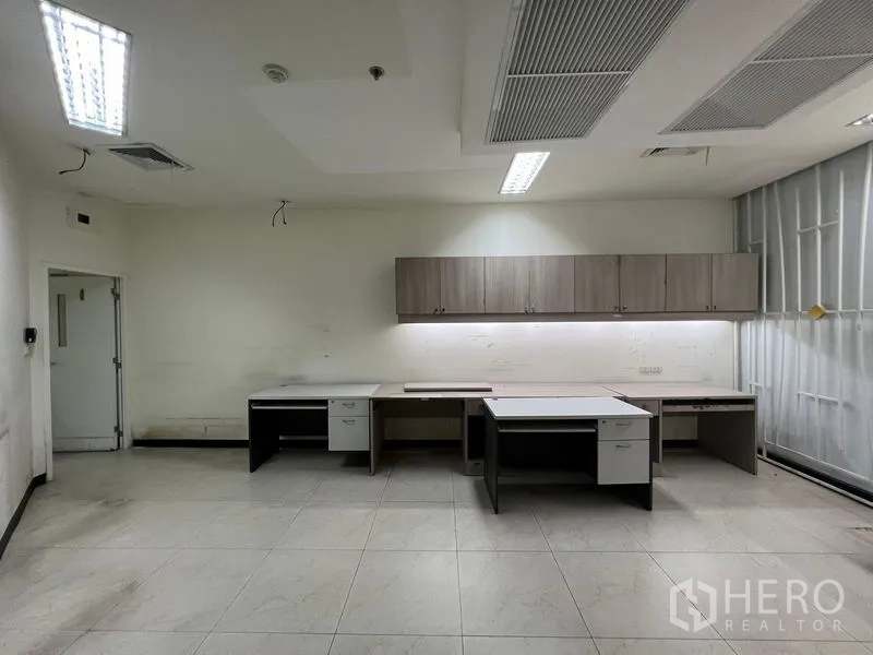 Retail Space for rent - Back office room with built-in desks, overhead cabinets, and bright lighting.