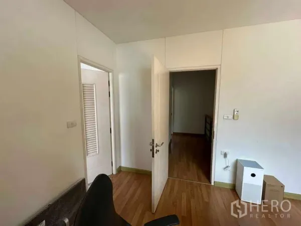 Home Office for rent in Chatuchak, Bangkok - Compact interior room with white walls, wood flooring, and doors opening to a hallway.