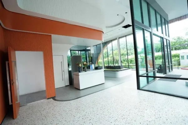 Standalone for rent in Bang Na, Bangkok - Double-height lobby with reception desk, terrazzo flooring and floor-to-ceiling windows.