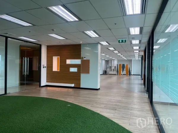 Office Space for rent in Chatuchak, Bangkok - Hallway view of modern office with feature wall panels, turf collaboration area and full-height glass partitions.
