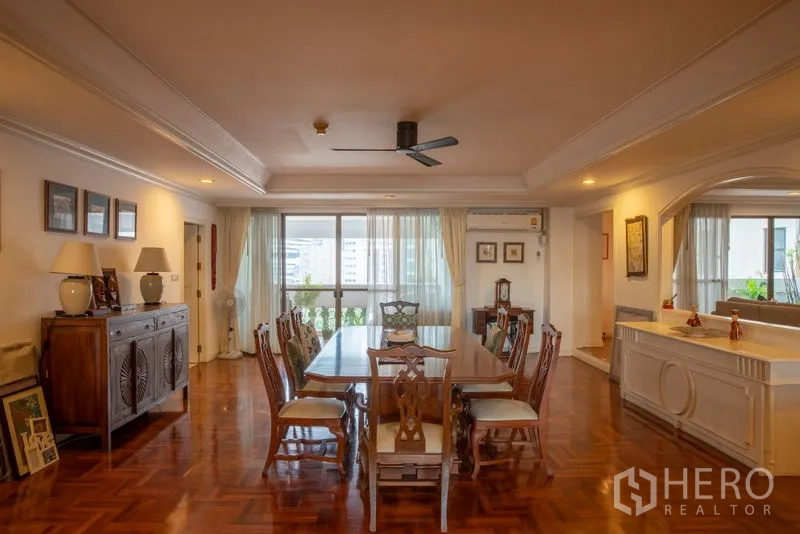 Condominium for rent in Khlong Toei, Bangkok - Spacious dining room with parquet flooring, ceiling fan, large windows and classic wooden furniture in a Bangkok condo.