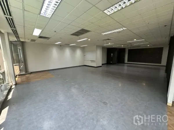 Office Space for rent - Large open-plan workspace with grid ceiling, air-conditioning and wide windows along one side.