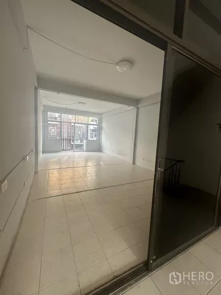 Shophouse for rent in Khlong Toei, Bangkok - Open-plan room viewed through a sliding glass frontage with tiled floor.