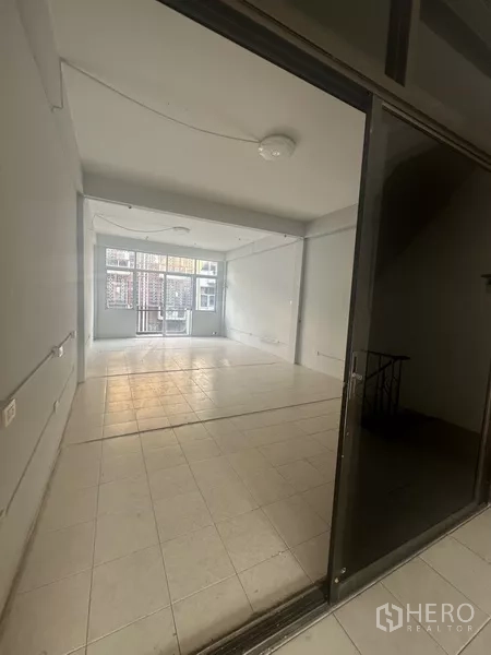 Shophouse for rent in Khlong Toei, Bangkok - Open-plan room viewed through a sliding glass frontage with tiled floor.