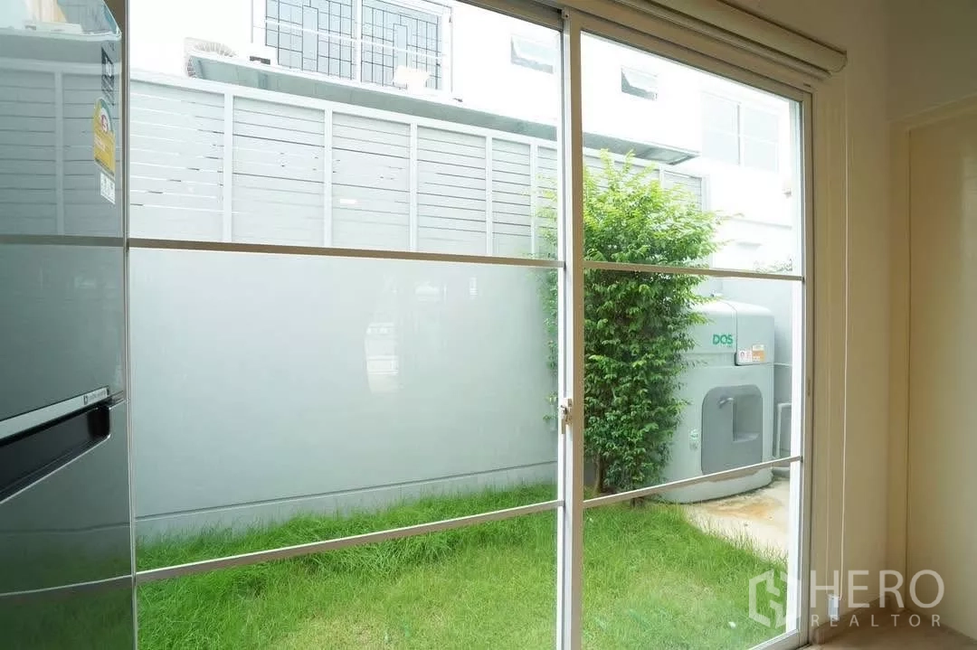 Townhouse for rent in Bang Phli, Samut Prakan - Rear lawn and utility tank viewed through sliding glass door