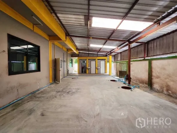 Warehouse for rent in Lat Krabang, Bangkok - Covered utility area with yellow beams, windows and service access beside the warehouse.
