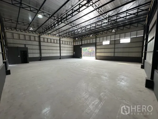 Warehouse for rent in Prawet, Bangkok - Spacious warehouse interior showing high steel truss roof, clerestory windows, bright lighting and a large front opening.