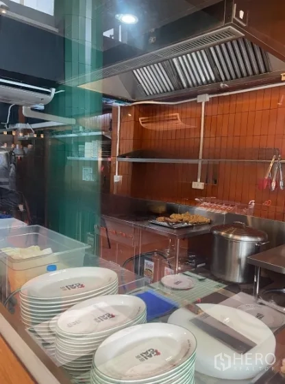 Shophouse for rent in Watthana, Bangkok - Open kitchen behind glass with stainless hood, grill and preparation area.