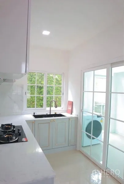 独立式住宅 出租在Bang Phli, Samut Prakan - 厨房水槽区，推拉玻璃门连接洗衣区与庭景。