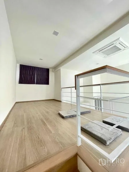 Townhouse for rent or sale in Prawet, Bangkok - Mezzanine loft with wood flooring, railing and ceiling cassette air conditioner.