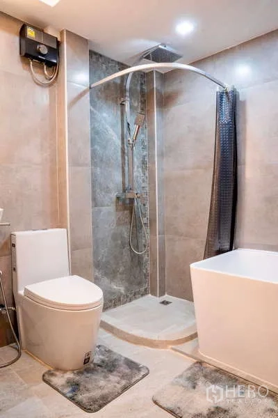 Townhouse for rent in Khlong Toei, Bangkok - Modern bathroom with glass shower, rain head, toilet and a freestanding bathtub.