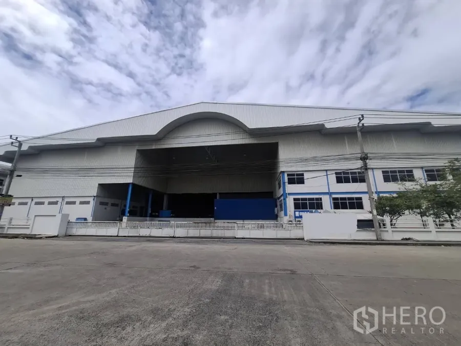 Factory for rent in Khlong Toei, Bangkok - Street view of a large standalone factory with a high gabled roof and gated loading bay.