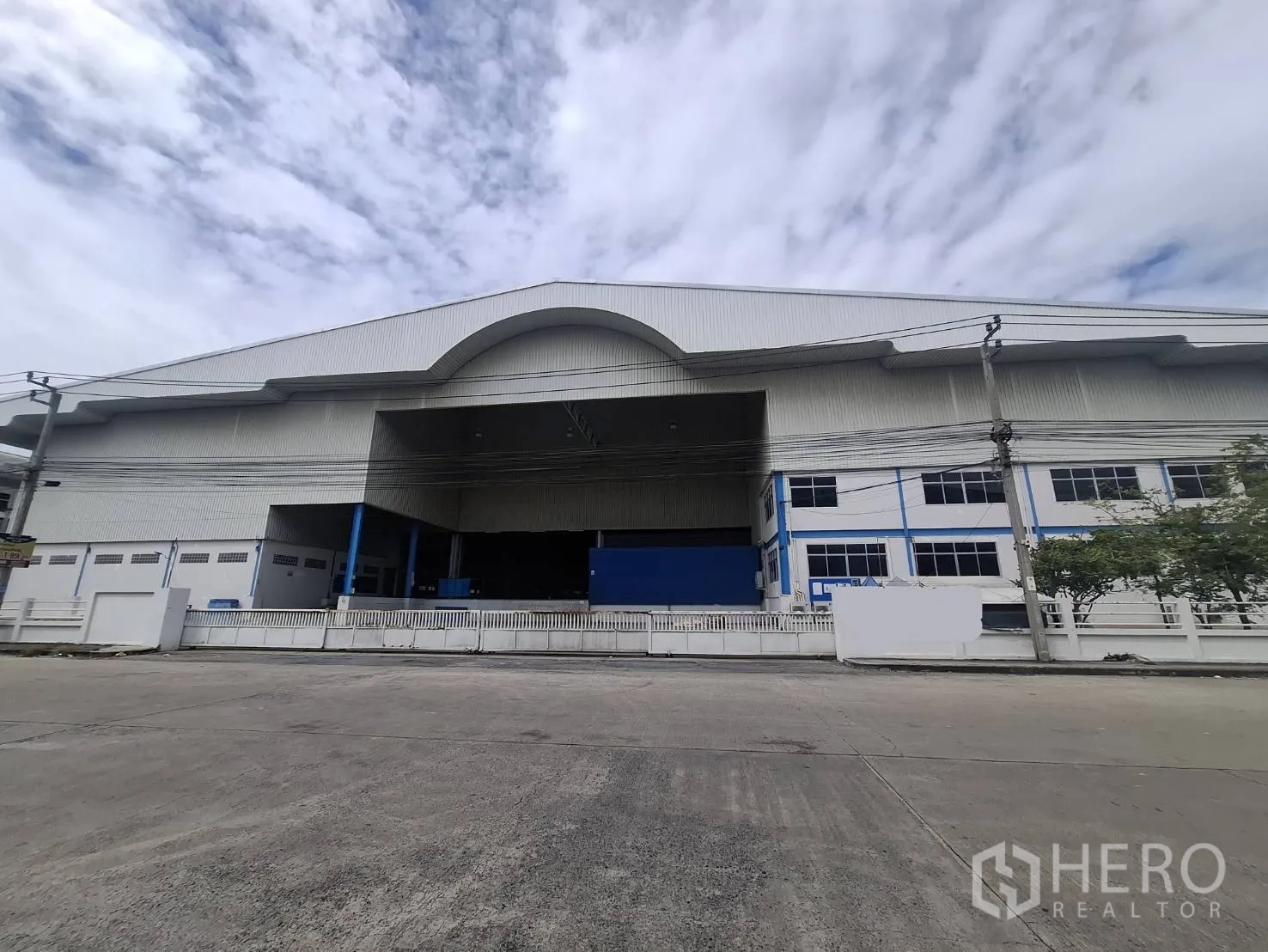 Factory for rent in Khlong Toei, Bangkok - Street view of a large standalone factory with a high gabled roof and gated loading bay.
