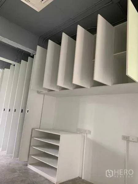 Office Space for rent in Khlong Toei, Bangkok - Row of vertical white storage cabinets and open shelving inside the office.