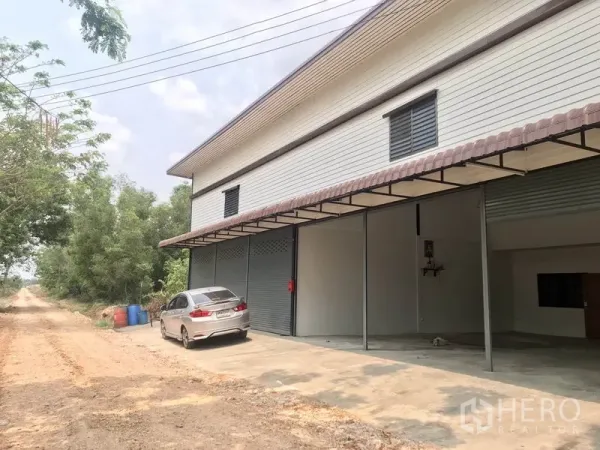 คลังสินค้า ให้เช่าในPathum Thani - ภายนอกมีประตูม้วนหลายบานพร้อมลานคอนกรีตสำหรับจอดรถและขนถ่าย.