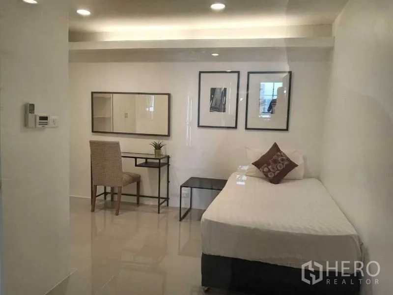 Condominium for rent in Khlong Toei, Bangkok - Second bedroom featuring a single bed, desk and framed art under soft recessed lighting.