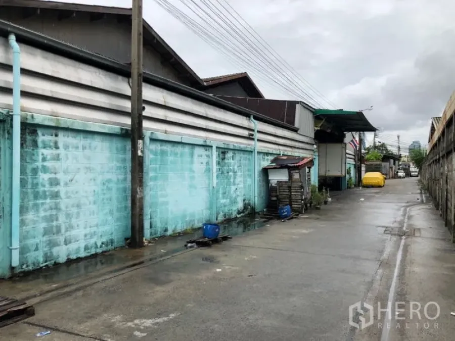 Warehouse for rent in Bang Kho Laem, Bangkok - Rear lane by the warehouse with loading dock and overhead awning on a rainy day.